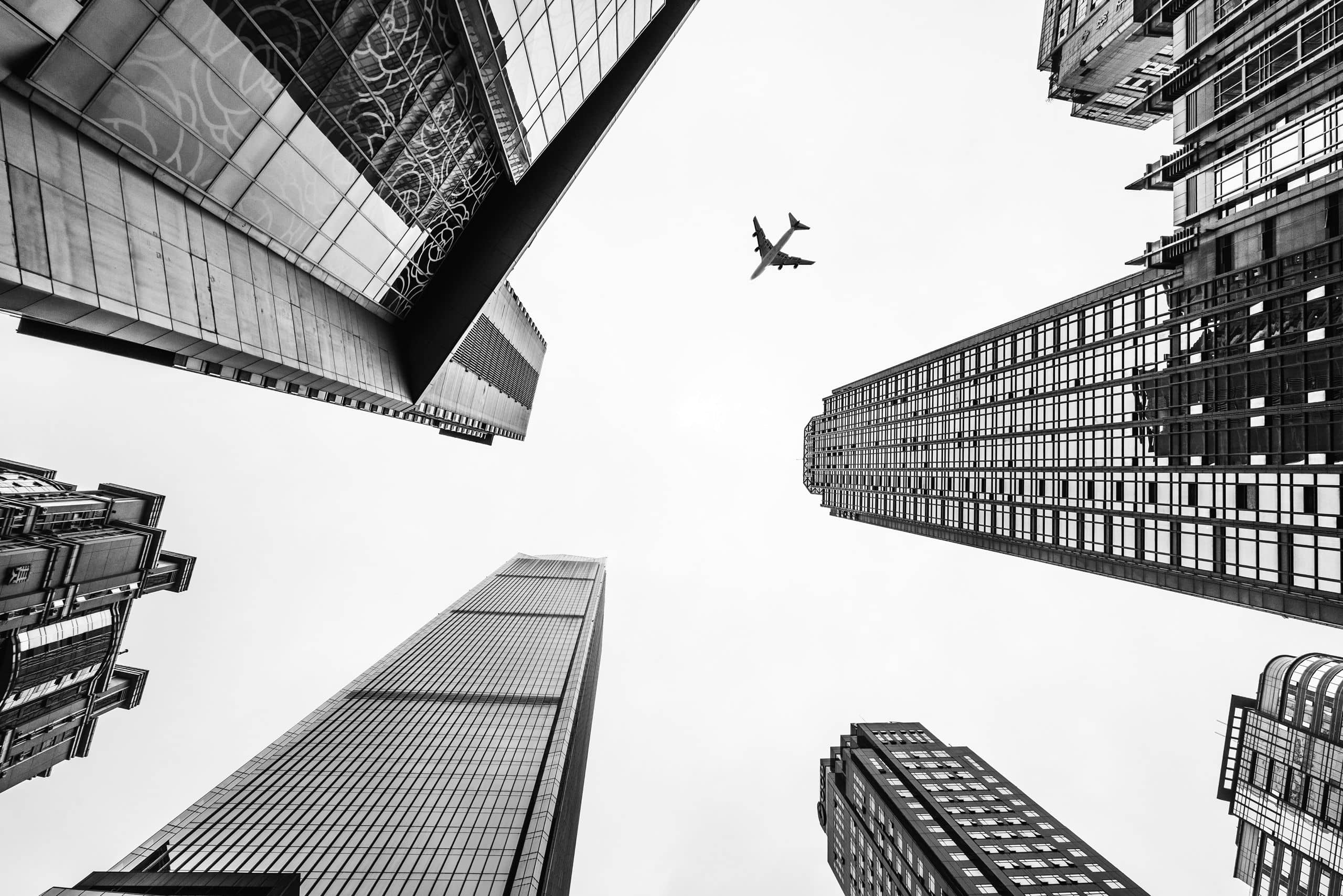 Immeubles vus en contre-plongée, un avion dans le ciel